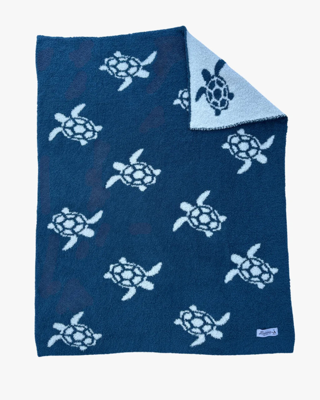 Flat lay of blue and white Sea Turtle Blanket with reversible sea turtle design