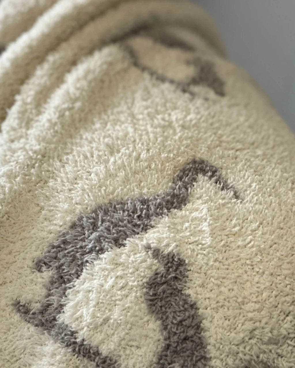 Close up on creamy white fabric with gray mother and baby heron silhouette