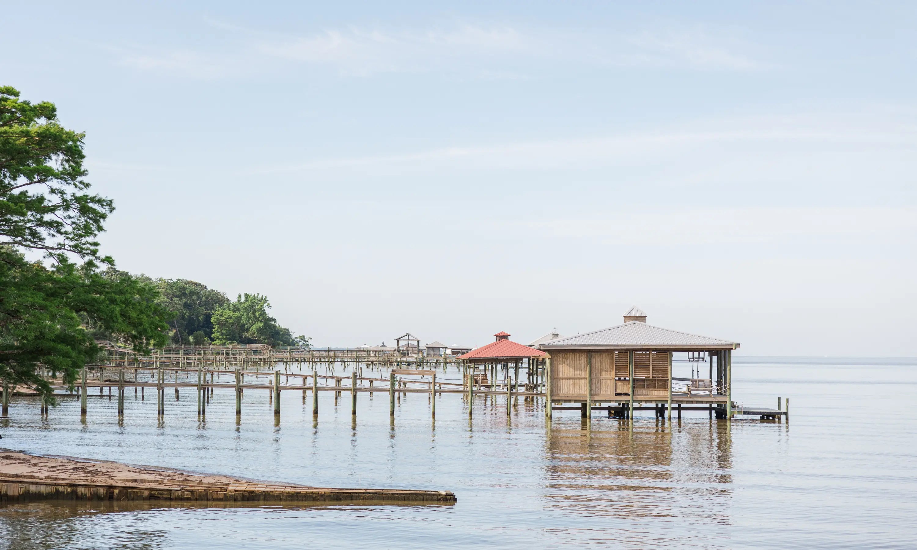 Scenic view of wooden piers and gazebos over calm water with trees and clear sky
