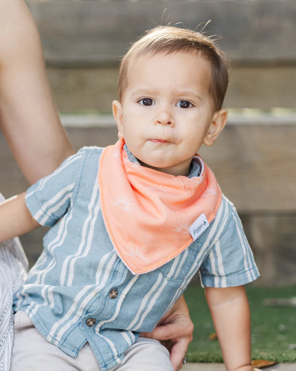 Toddler boy wearing a orange with white sunset pattern bandana bib by Baldwin Baby Co