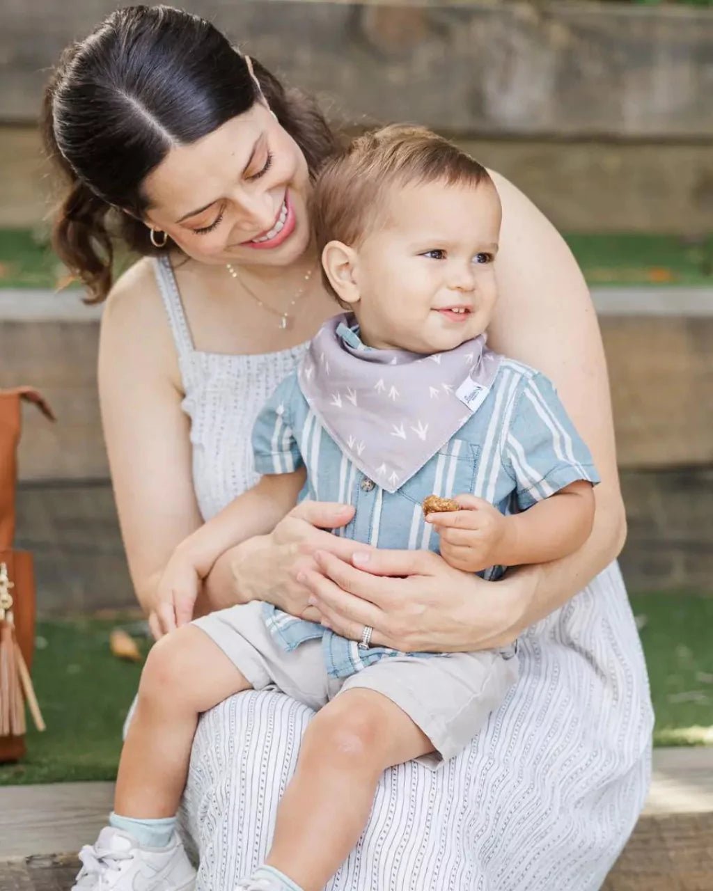 Toddler boy wearing a brown with tan turkey track pattern bandana bib by Baldwin Baby Co
