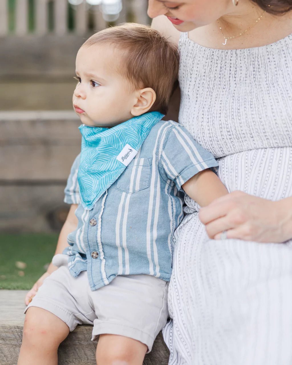 Toddler boy wearing a white with green monstera pattern bandana bib by Baldwin Baby Co