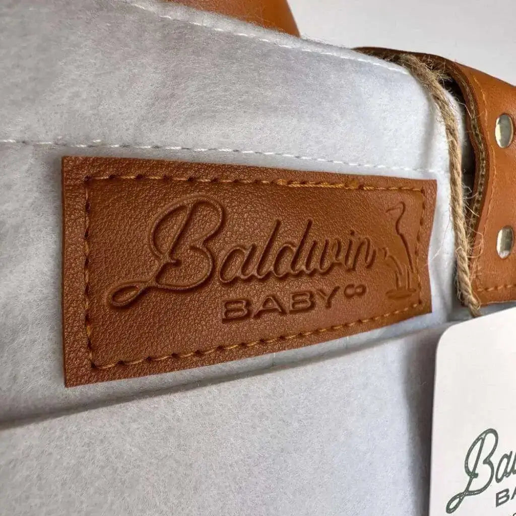 White felt diaper caddy with light blue tint and Baldwin Baby Co logo on leather accents