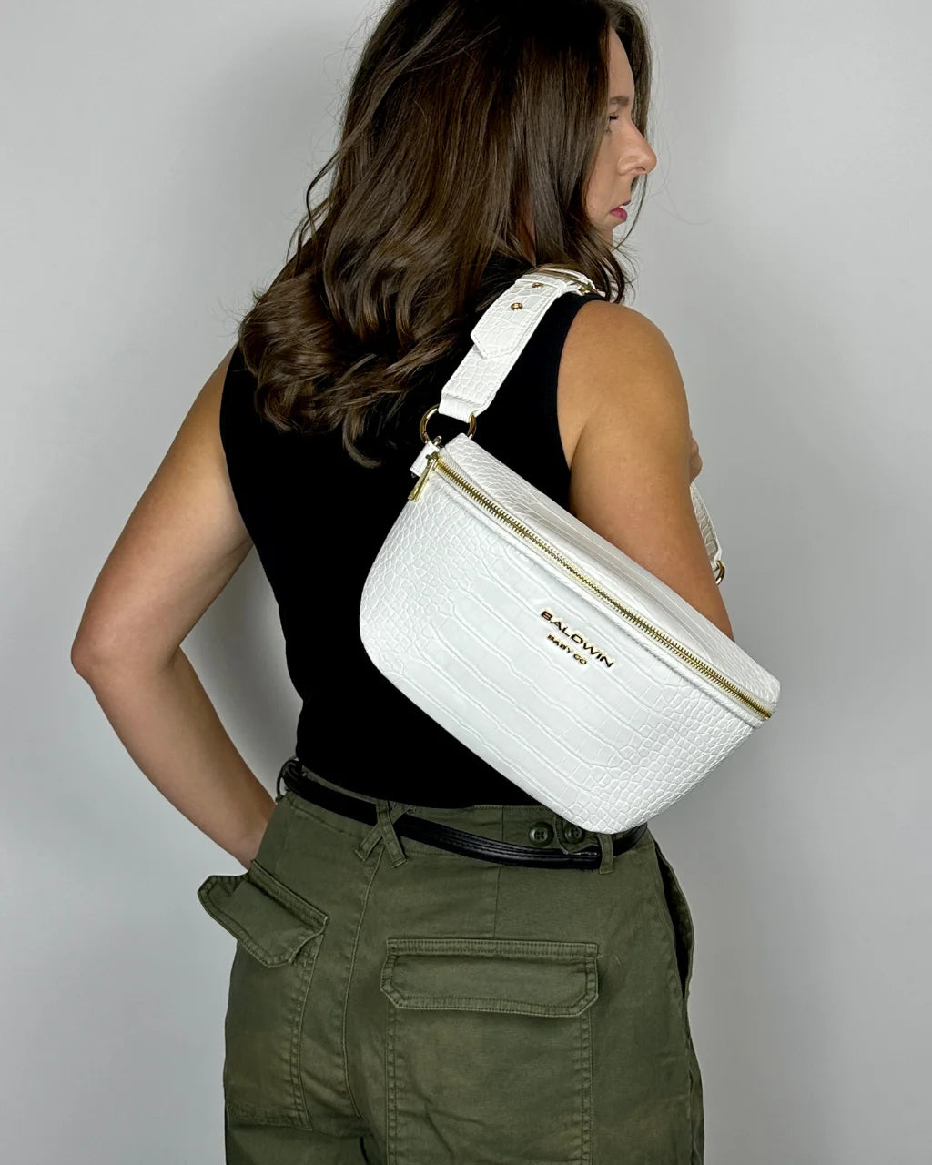 Woman in black shirt wearing white faux croc belt bag on shoulder with gold hardware