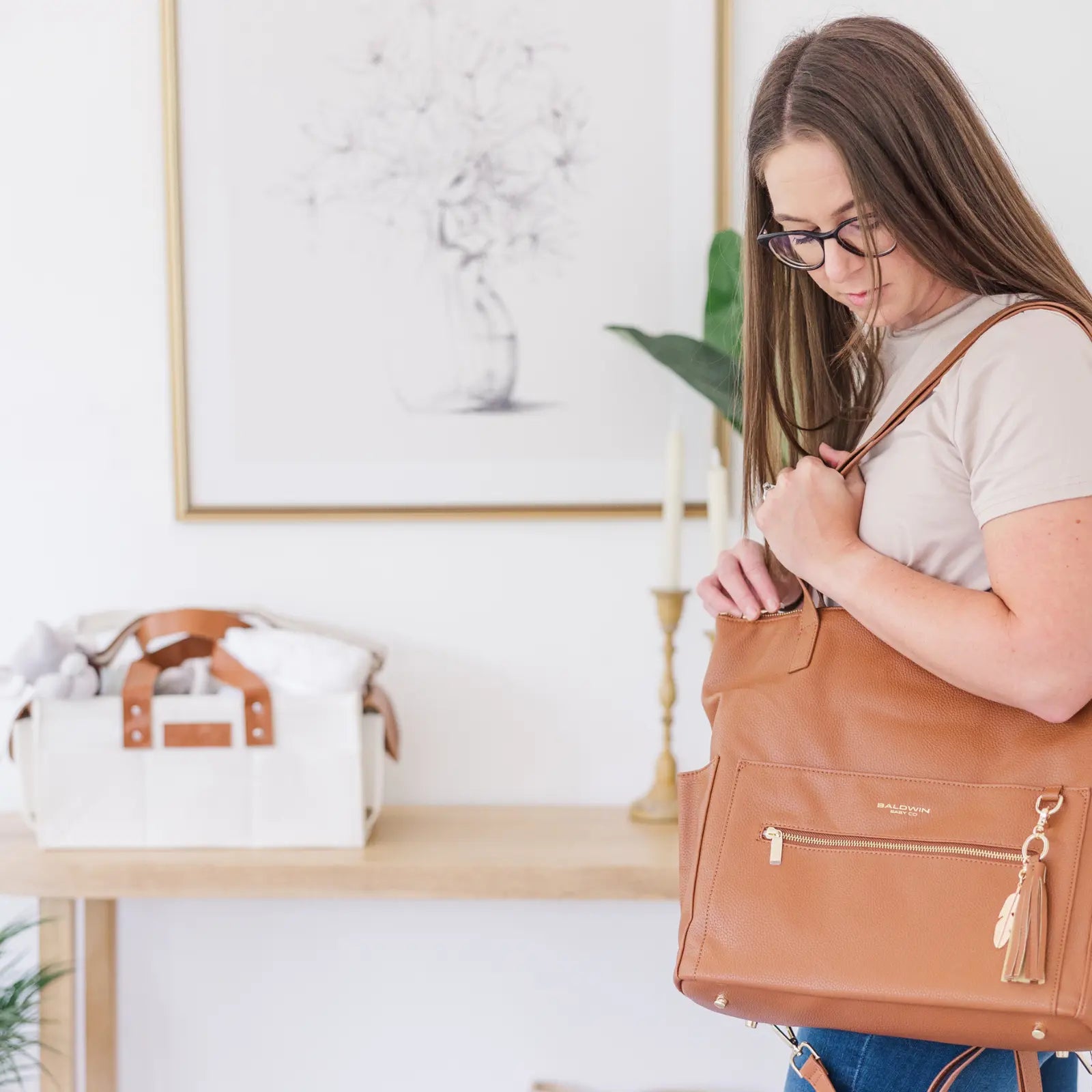 women looking at a brown leather diaper bag leather tote with gold feather tassel