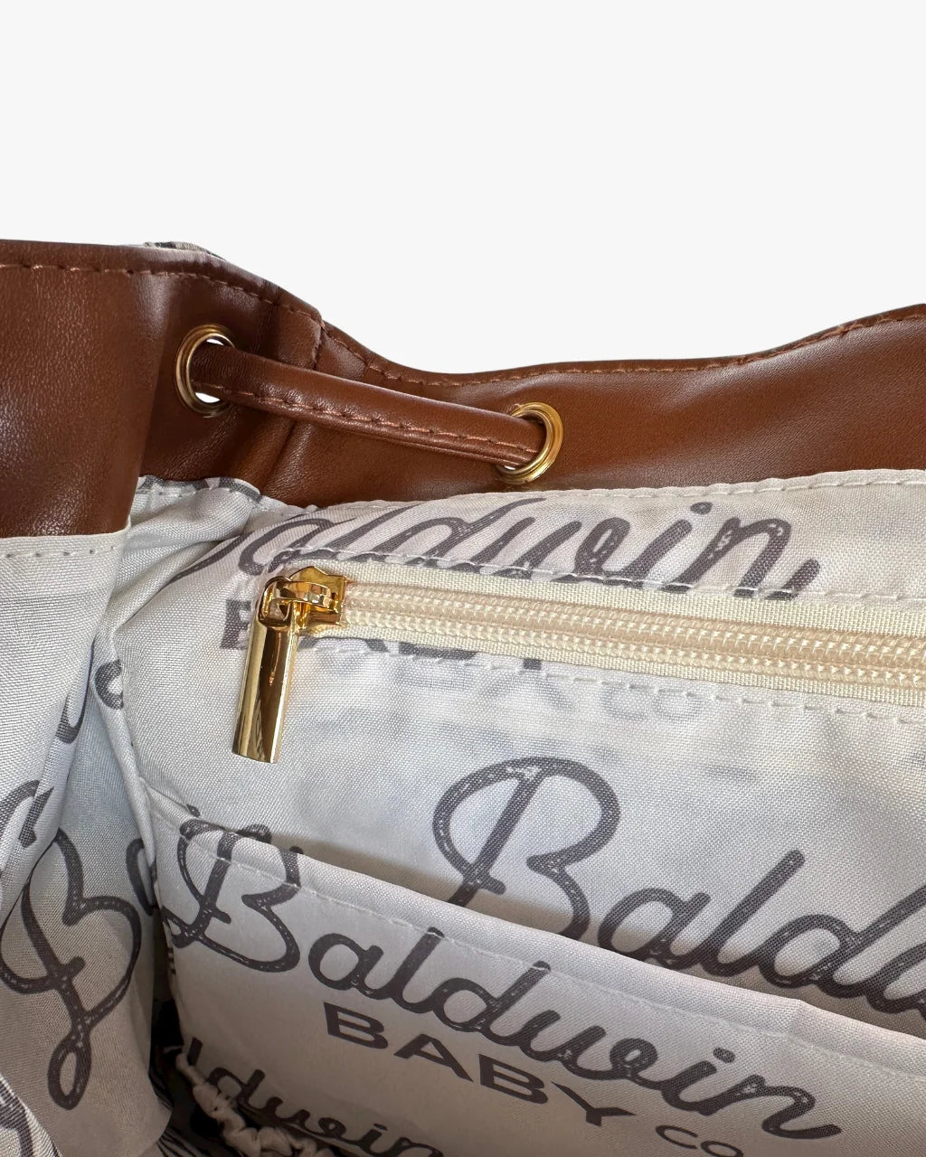 Close-up of zip pocket and logo lining inside houndstooth diaper bag with gold hardware