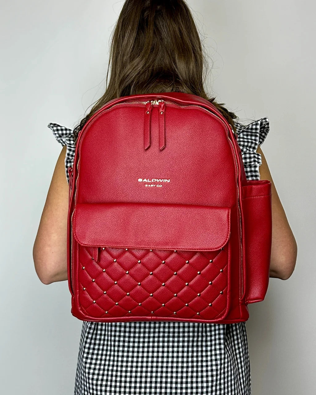 Woman in black & white dress wearing red diaper backpack, stylish and functional