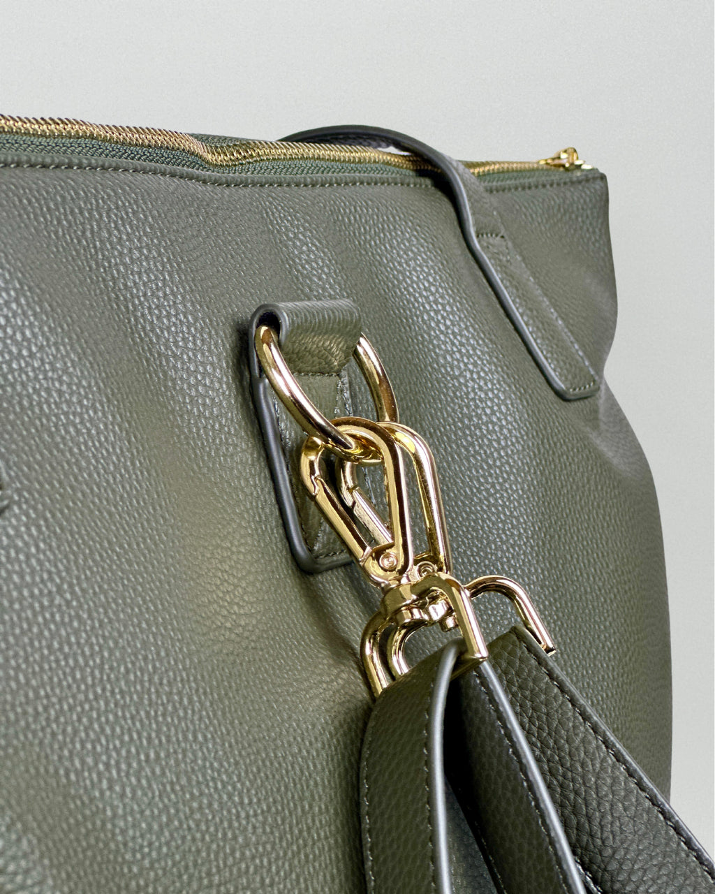 Close up view of vegan green leather diaper bag with gold hardware