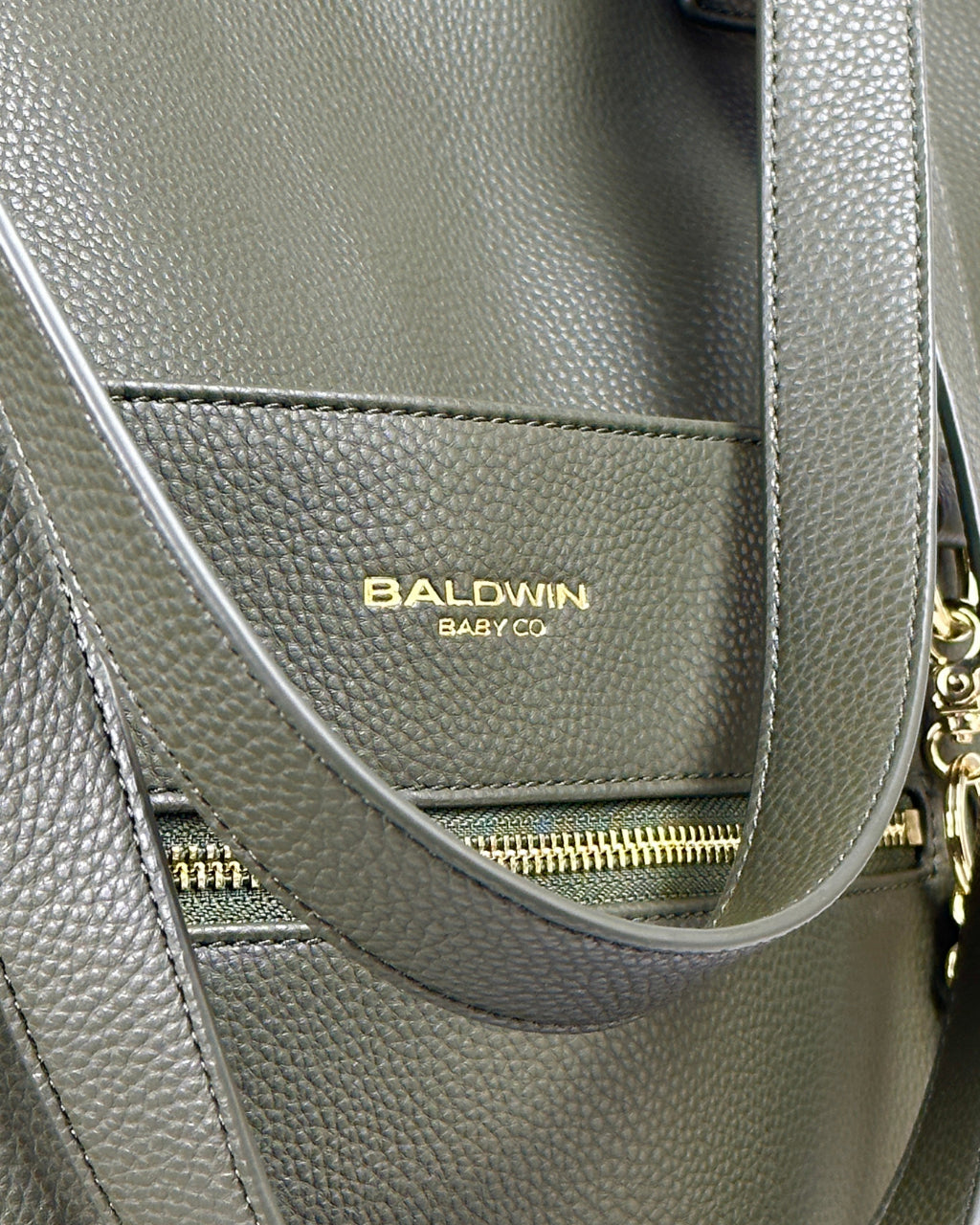 Close up view of Baldwin Baby Co logo on vegan green leather diaper bag with gold hardware