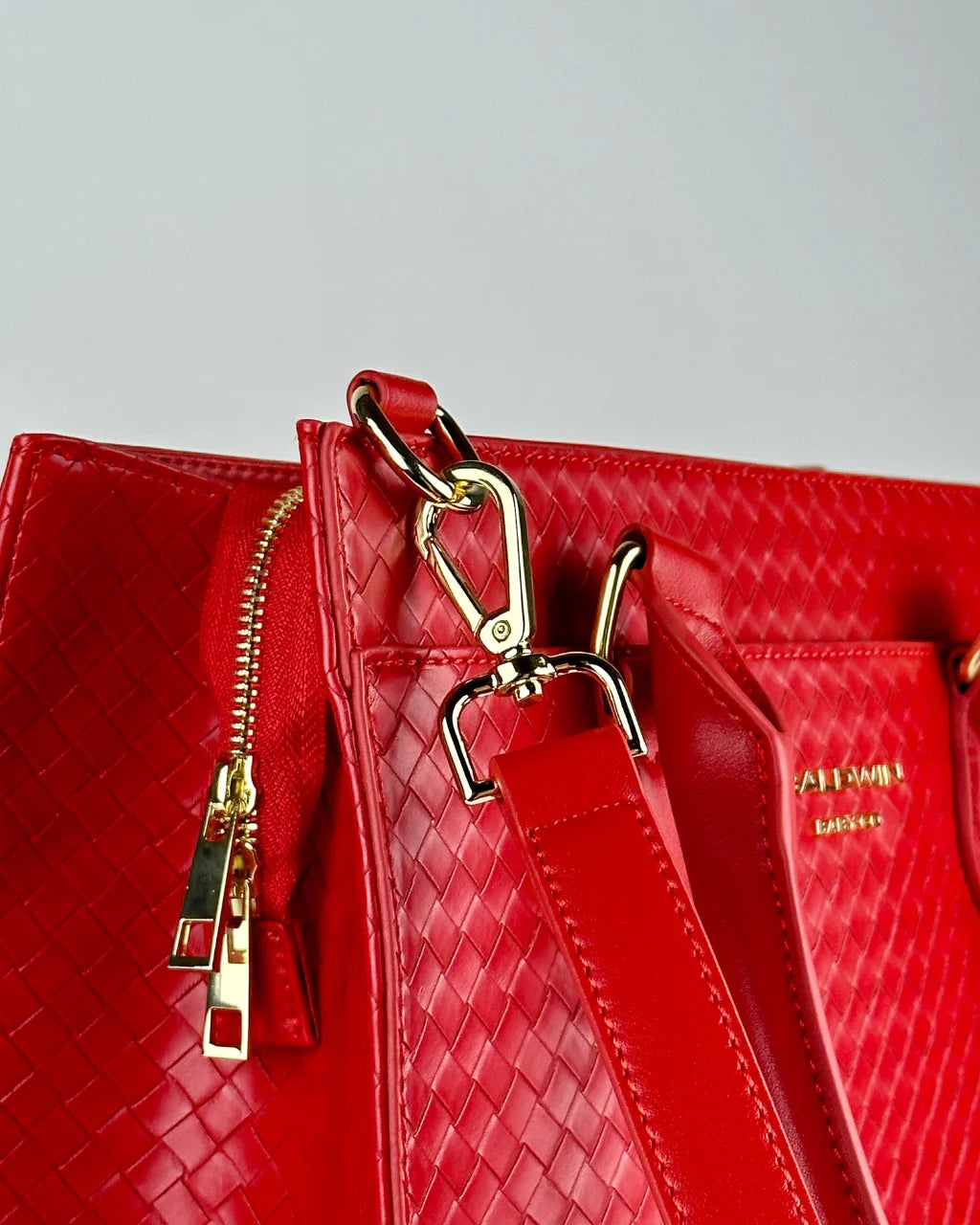 Highlighting the elegant gold hardware details and vibrant red quilted texture of the Cardinal Montrose diaper bag.