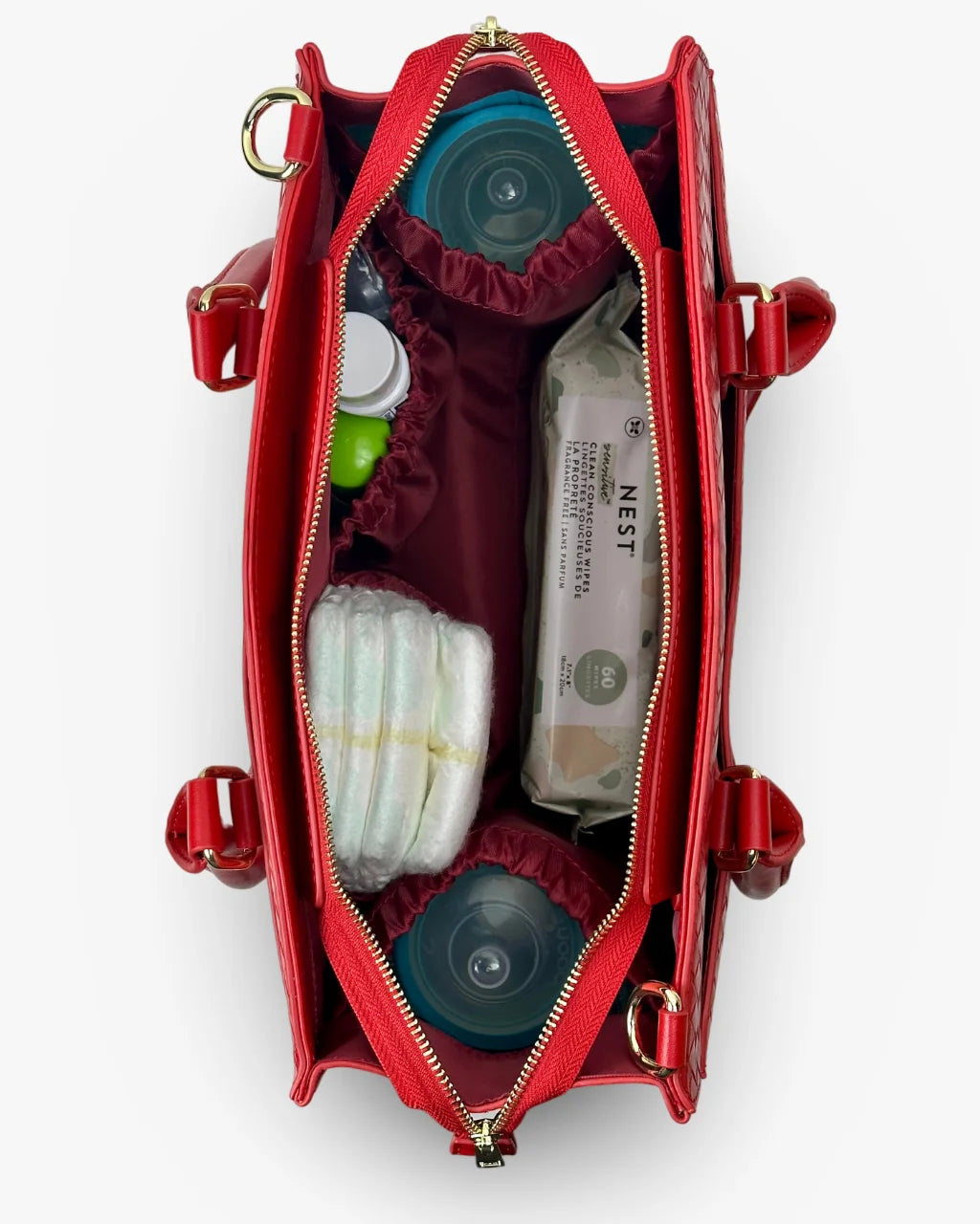 Highlighting the functional and stylish interior of the red diaper bag tote, packed with baby essentials, including bottles and diapers.