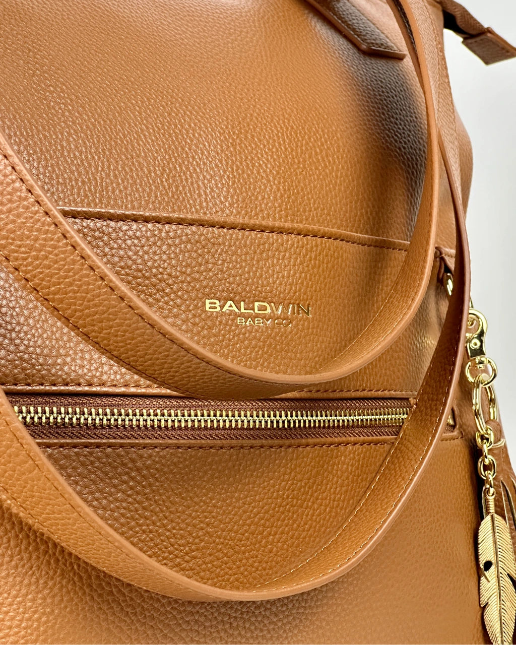 Close up view of Baldwin Baby Co logo on vegan brown leather diaper bag with gold hardware