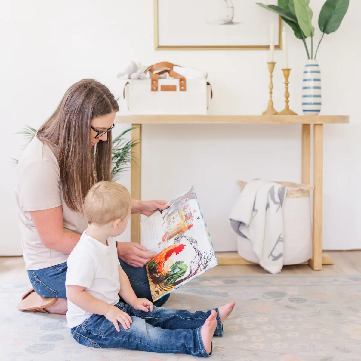 Woman reading to young boy on floor with white diaper caddy on table in background