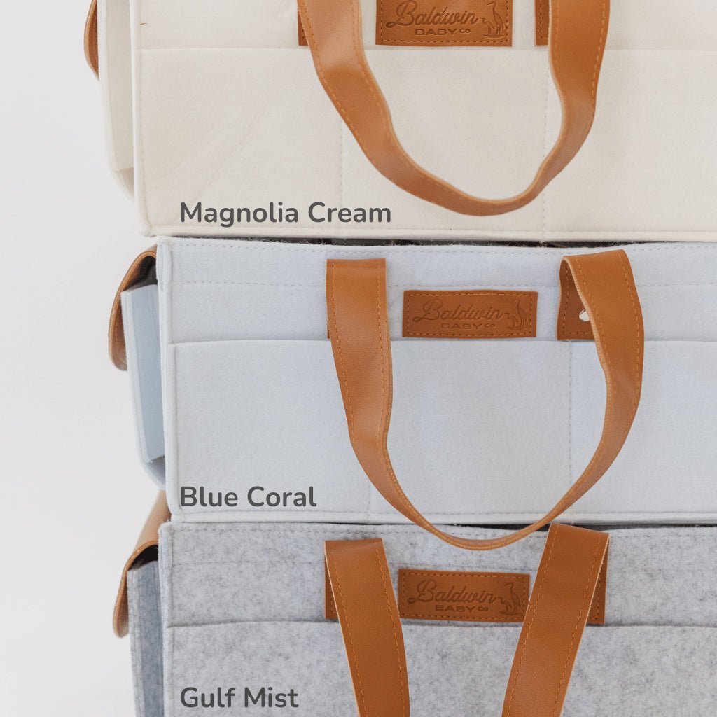 gray, blue, and white diaper caddies with brown leather handles stacked on top of each other
