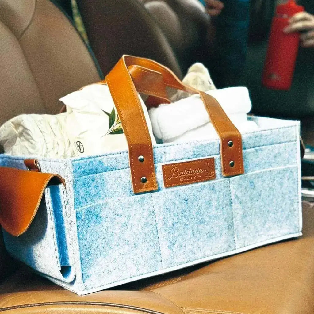 heather gray diaper caddy made of felt packed with baby essential sitting in car seat