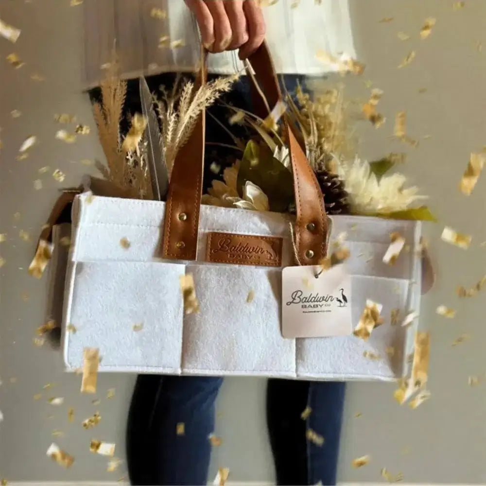 Cream felt diaper caddy with leather accents, floral decor, and gold confetti overlay