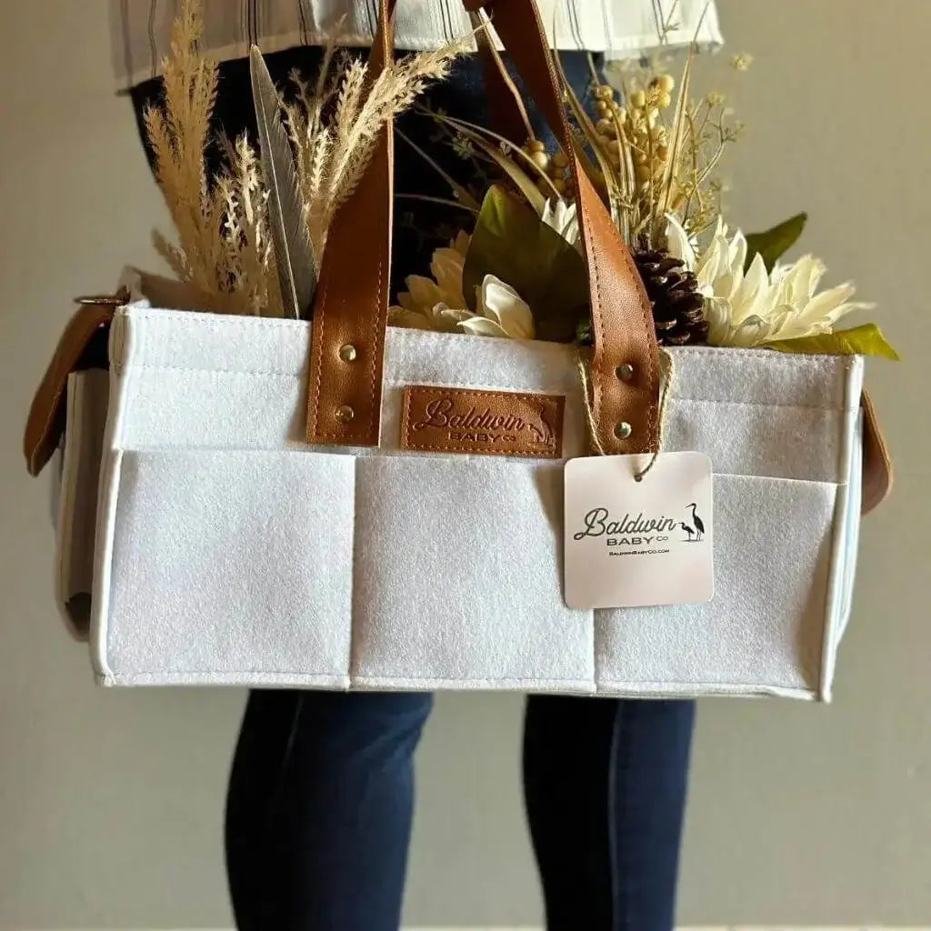creamy white diaper caddy made of felt with leather accents and straps decorated with florals