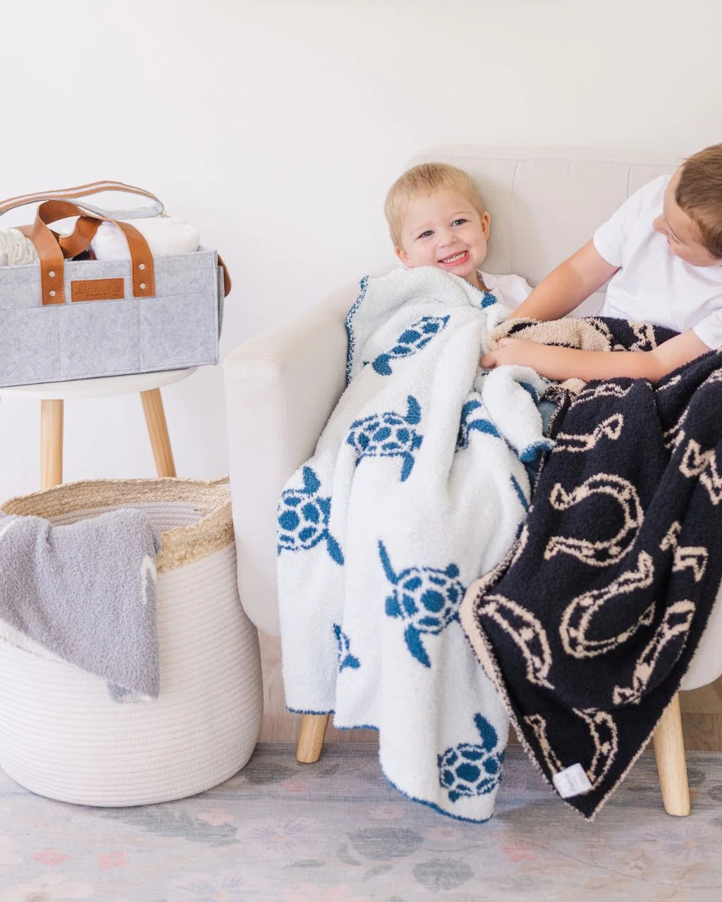 Two boys sitting in chair with sea turtle and horseshoe print baby blankets