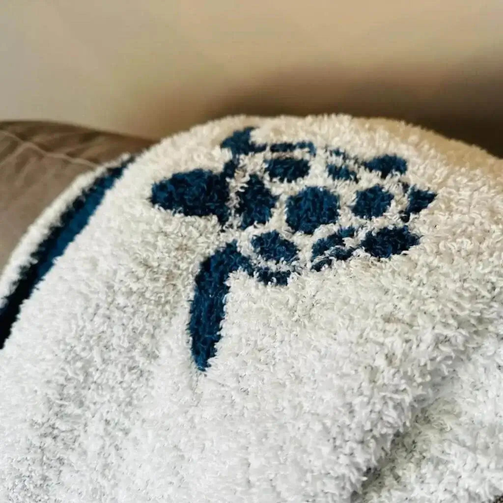 White with blue sea turtle pattern fabric draped over couch