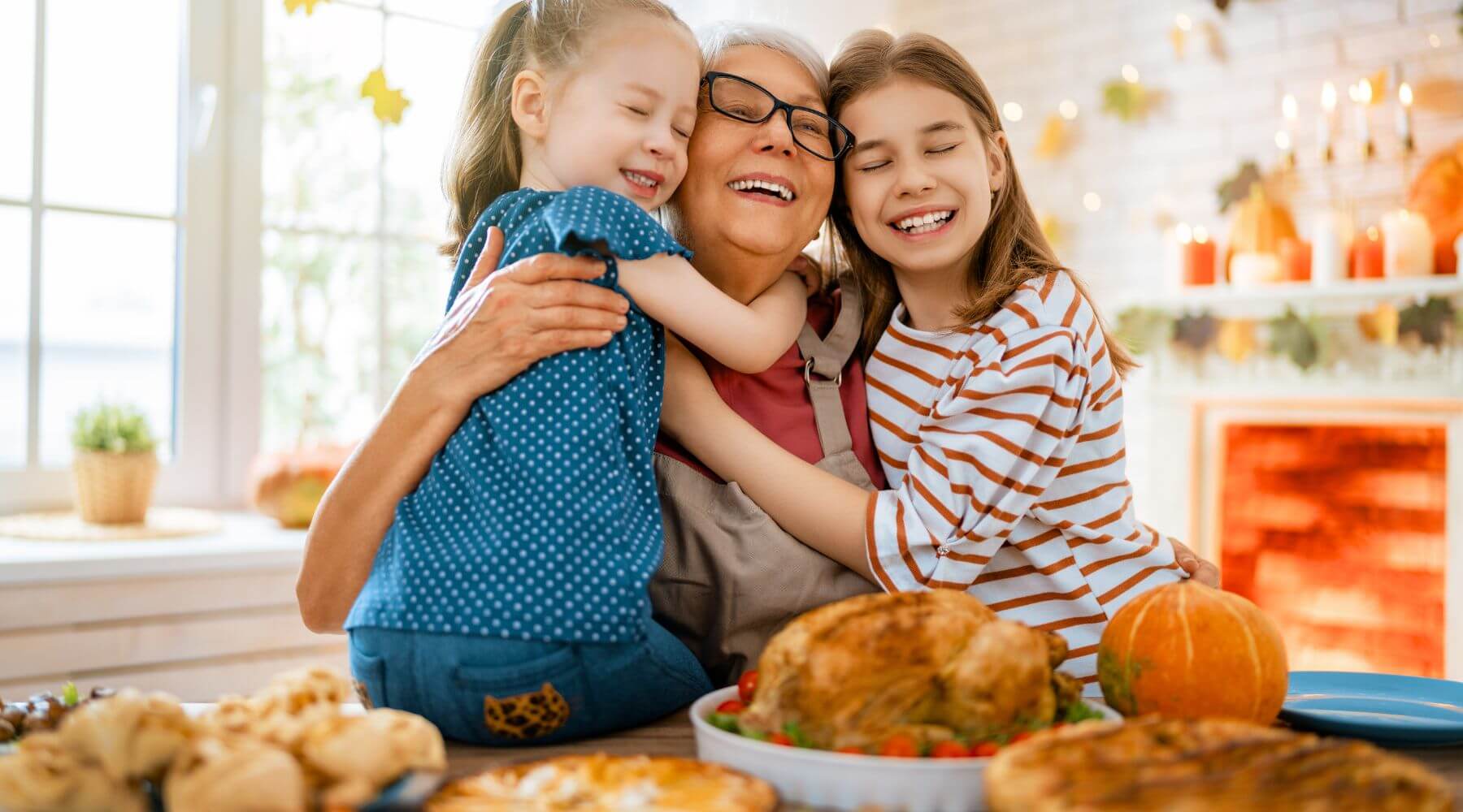 An elderly woman hugging two young girls at a festive Thanksgiving table, smiling with joy. The table is set with a traditional Thanksgiving meal, including a turkey and pumpkin, in a warm and cozy dining room.