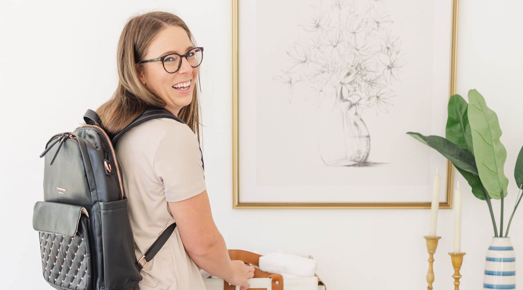 woman wearing black leather diaper bag backpack looking over her shoulder smiling