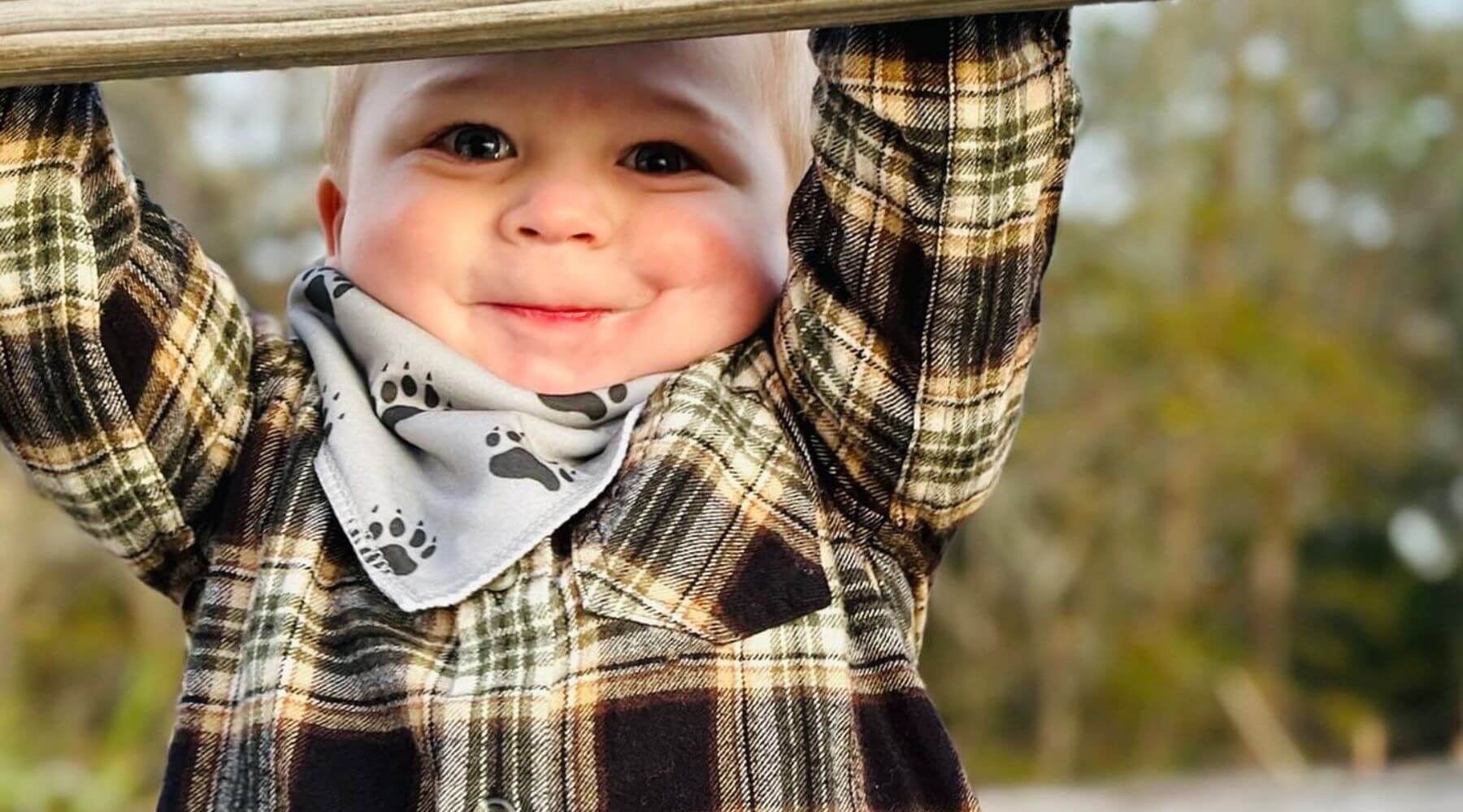 young boy wearing a bib with bear paw prints on it