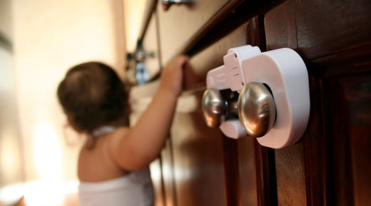 Baby attempting to open a kitchen cabinet with a safety lock installed.