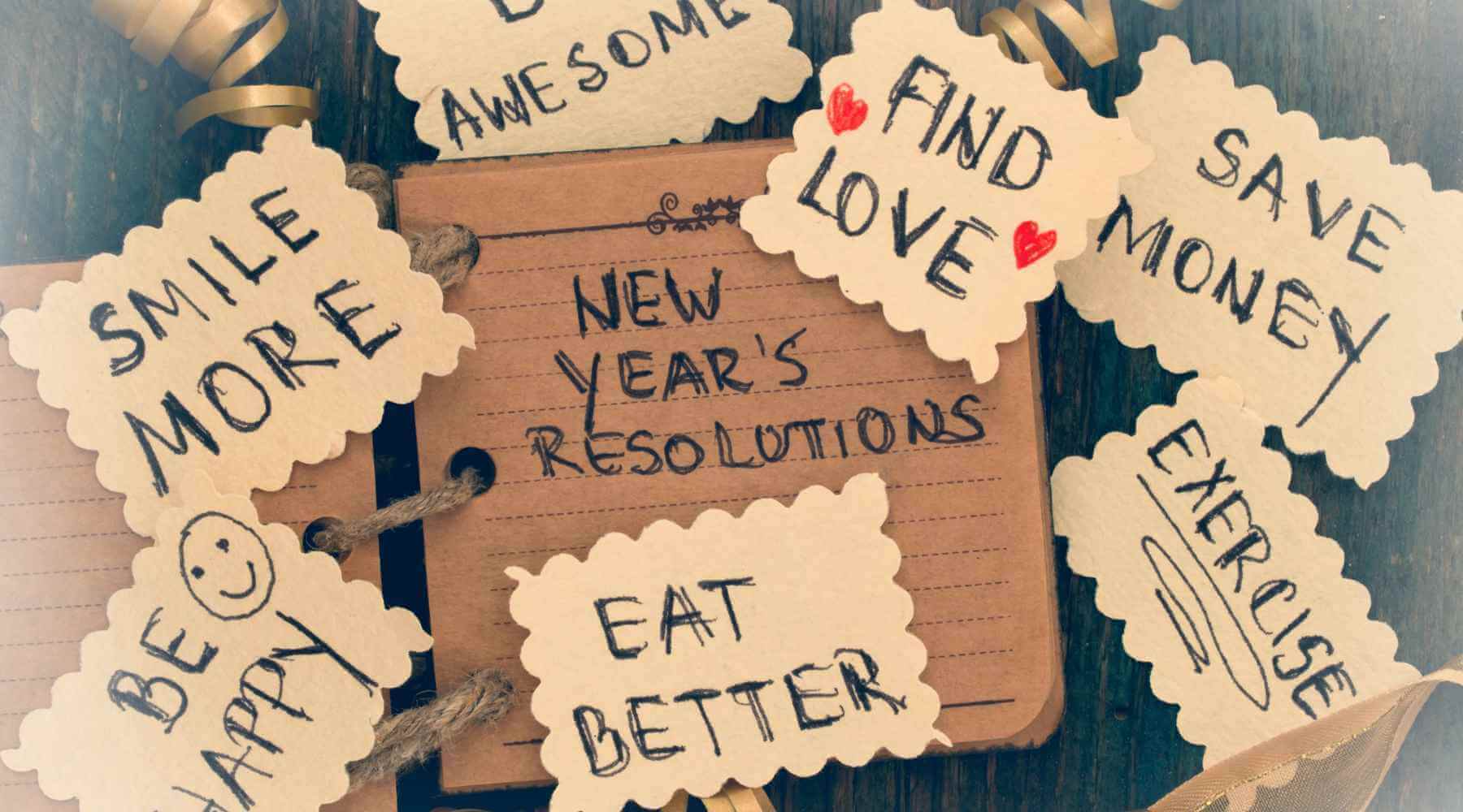 A collection of handwritten New Year's resolutions on small tags, featuring goals like 'Smile More,' 'Eat Better,' and 'Exercise.