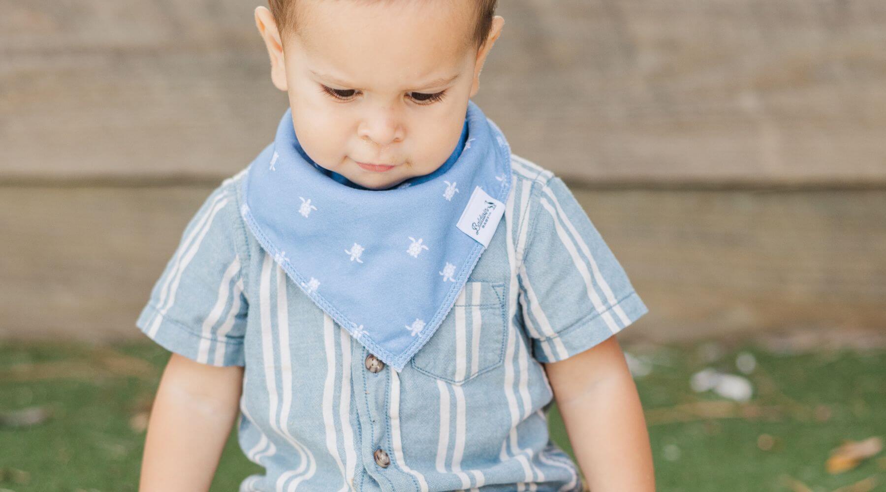 toddler wearing a bib looking towards ground