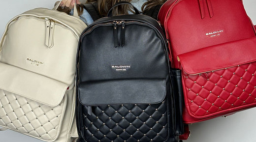 A variety of Baldwin Baby Co diaper bags, including a beige, black, and red backpack design