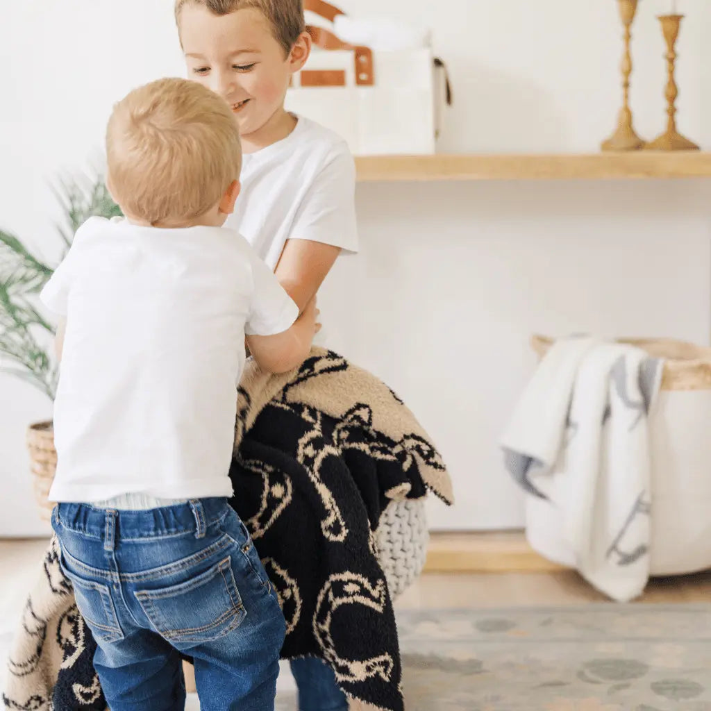 two young boys with a black and tan horseshow blanket