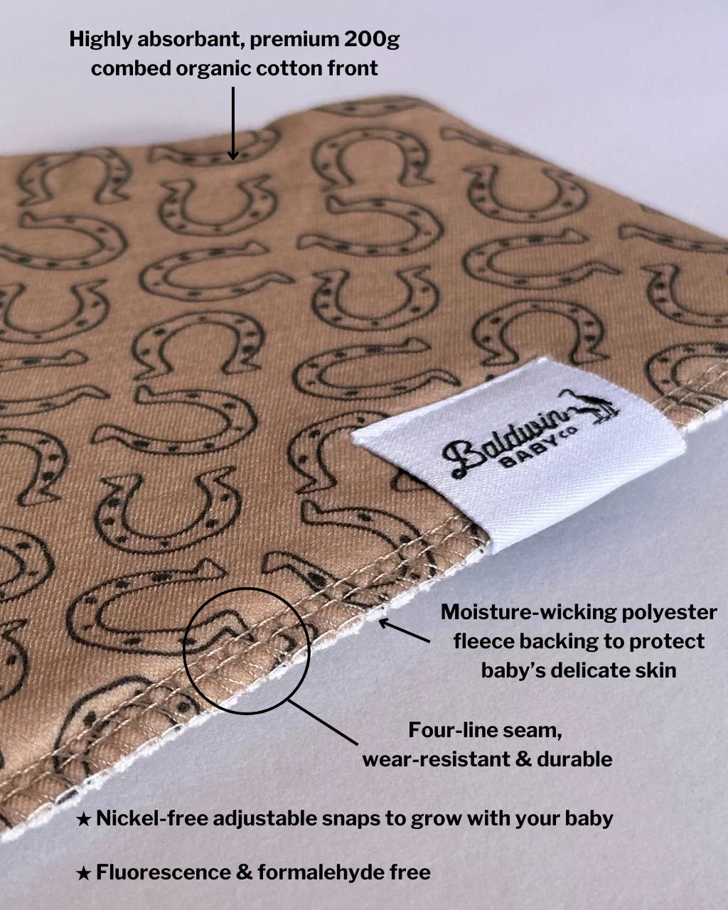 Close up of a tan with brown horseshoe pattern bandana bib with a white Baldwin Baby Company logo tag