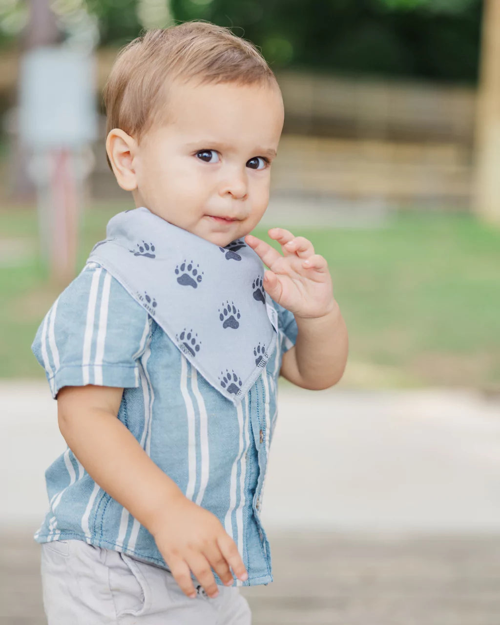 Toddler boy wearing a gray with black bear foot print pattern bandana bib by Baldwin Baby Co