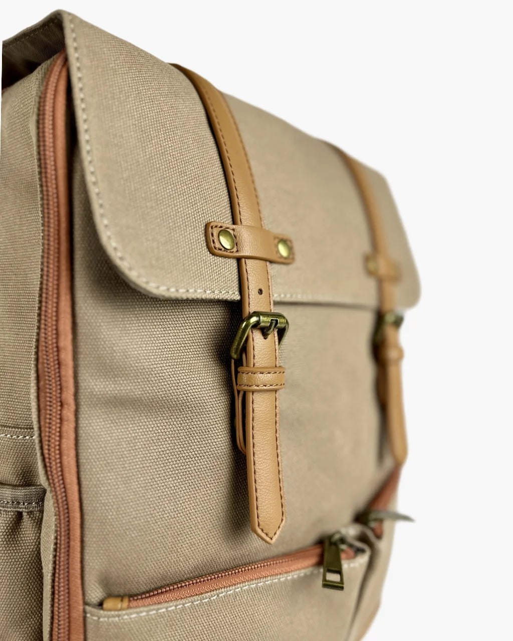 Close-up of the tan leather buckle straps and flap detail of the beige canvas diaper backpack, showing brass hardware and meticulous stitching.