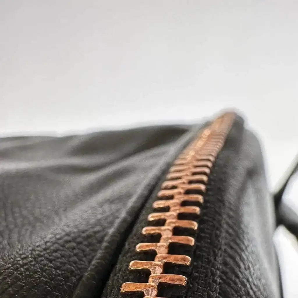Close up of rose gold zipper on black leather backpack diaper bag