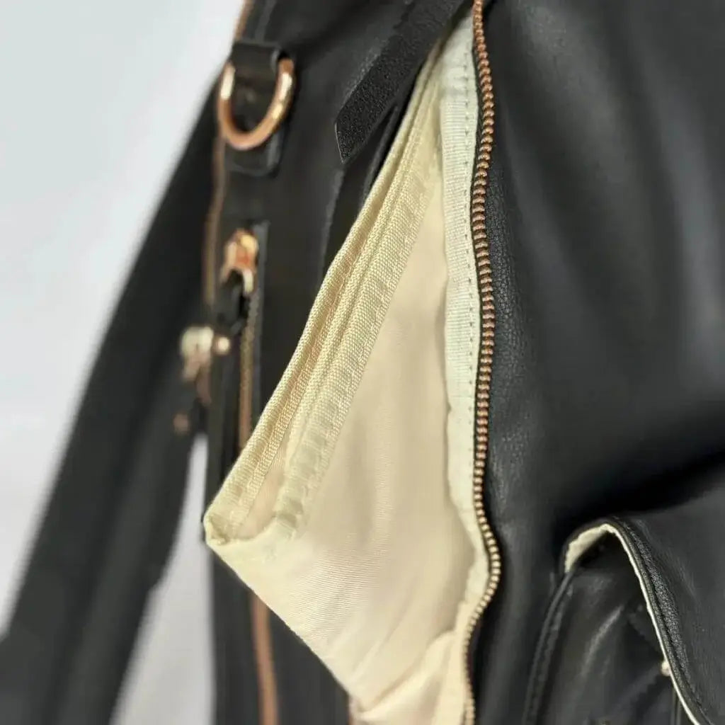 Close up of changing pad peeking out of a black leather backpack diaper bag