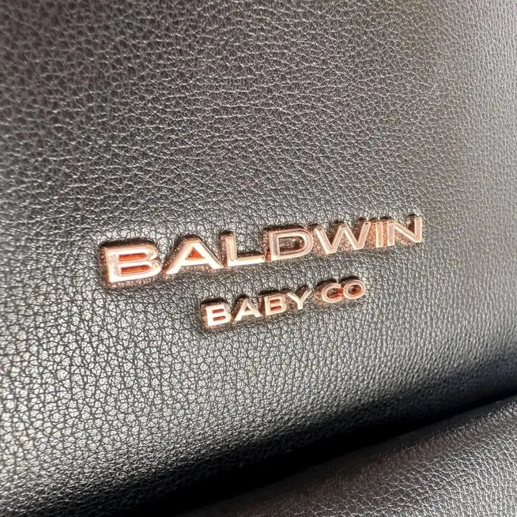 Close up of rose gold Baldwin Baby Company logo on black leather 
