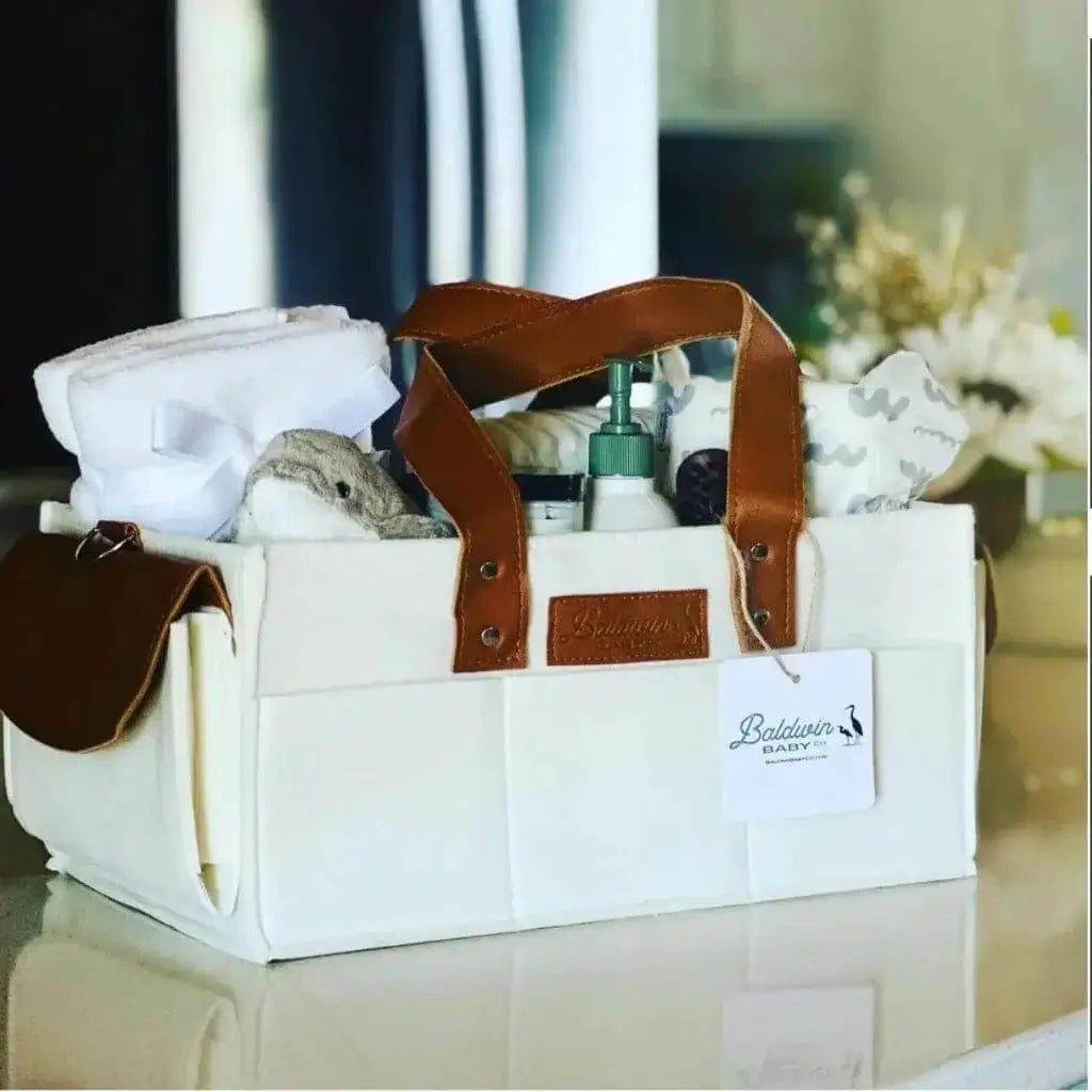 creamy white diaper caddy made of felt with leather accents and straps full of baby needs