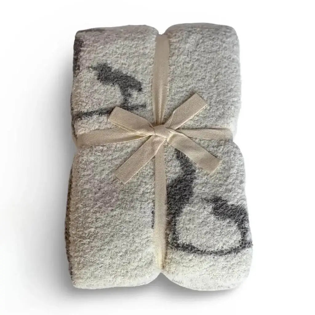 Creamy white with a gray mother and baby heron silhouette pattern blanket folder neatly and tied with a white bow