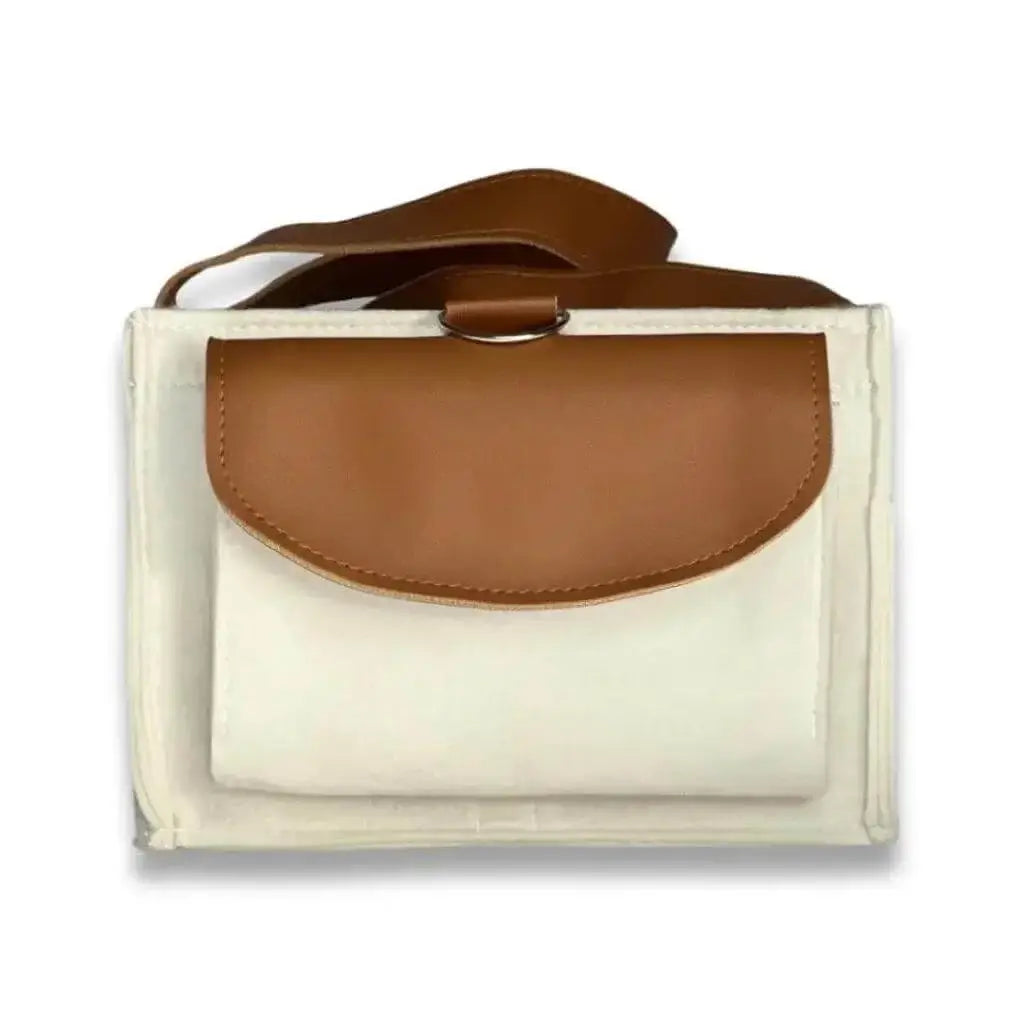 side view of creamy white diaper caddy made of felt with leather straps and pocket flap