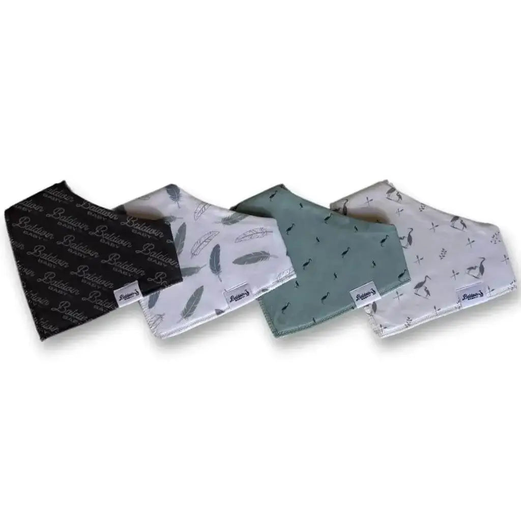 Set of four bandana bibs on a white background. Charcoal with light gray Baldwin Bay Co pattern, white with green and transparent feathers, green with dark gray herons, and creamy white with Baldwin Baby Co's signature heron pattern