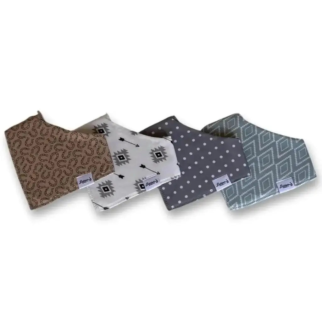 Set of four bandana bibs on a white background. Tan with brown horseshoes, creamy white and black arrows, gray with white polka dots, and green with white western or Aztec-style diamond patterns
